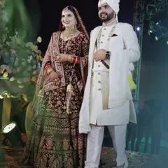 Make your wedding unforgettable with coordinated outfits. The bride's deep maroon lehenga perfectly complements the groom's classic white sherwani.