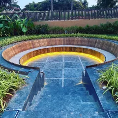 The steps leading down into the sunken lounge are made of dark stone, contrasting with the warm wood of the bench.