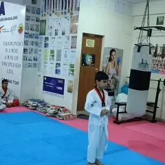 A young student stands alone on the mat, ready to begin his belt test. This moment builds immense courage and confidence.