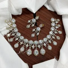 A stunning AD necklace set laid out to show its full design. This piece is available in multiple vibrant colors like ruby red, emerald green, pastel blue, and sapphire blue, featuring teardrop-shaped stones.