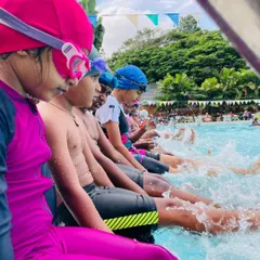 The simple joy of making a splash! Young swimmers in our Learn to Swim program have fun kicking at the edge of the pool, an essential drill for building leg strength and getting comfortable with the water.