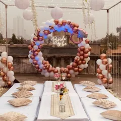 A still shot capturing the beautiful details of the terrace party decor. The rose gold and white balloon ring with the "Bride to be" sign serves as the central focal point for this elegant floor seating arrangement.