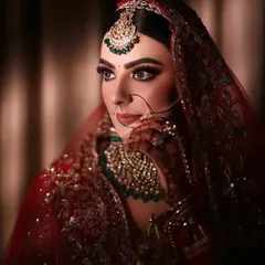 A close-up of this traditional bridal makeup, focusing on the rich color palette. The deep red lehenga is balanced with emerald jewelry and a makeup look that features a defined eye and flawless base.