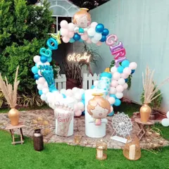 A fun gender reveal or baby shower setup. The decor features a circular balloon arrangement with "Boy" and "Girl" foil balloons, along with other baby-themed props in a pink and blue color scheme.