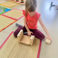 This girl is focused on building a stable structure on her mat. Block play allows children to test their ideas about balance, symmetry, and gravity in a hands-on way.