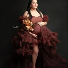 So much glamour in one photo. This mom-to-be looks incredible in a ruffled, high-slit brown gown against a classic dark backdrop, creating a powerful and elegant portrait.