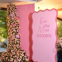 A chic and modern floral backdrop we designed for a bridal shower. The "Kiss the Miss Goodbye" sign is paired with an asymmetrical pillar of lush pink and peach roses, creating a stylish and fun photo opportunity.