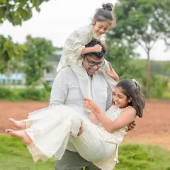 The pure fun of an outdoor family session. This playful shot of a parent lifting and carrying two laughing children perfectly captures the wild, happy chaos we love to photograph.