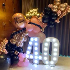 Hello, 40! We created this chic and modern backdrop for a 40th birthday, featuring a stylish pink, black, and rose gold balloon garland, a neon "Happy Birthday" sign, and large marquee numbers.