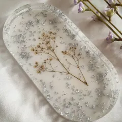 A closer look at the oval trinket tray, featuring preserved baby's breath and silver flakes. The design is delicate and adds a touch of nature to your decor.