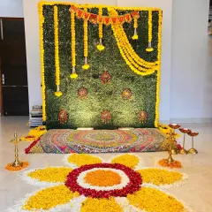 A straight-on shot of the Annaprashan backdrop. The lighting highlights the texture of the green wall and the bright yellow of the genda phool, making it perfect for photos of the baby and family.