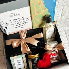 A travel-themed birthday hamper for him, complete with a personalized card, a 'Wanderlust' frame, a 'Love Story' candle, and of course, Nutella.