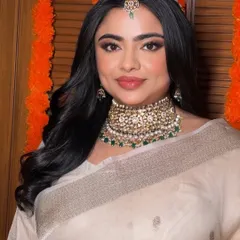 A beautiful bridal glow in an elegant ivory saree. The makeup is soft and defined, with a focus on the eyes and a traditional maang tikka.