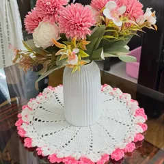 My white and pink floral-edged doily serves as a beautiful base for a vase of flowers, protecting your table and adding a delicate touch.