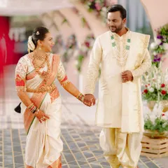 For this beautiful wedding, I designed a coordinated look for the couple. The bride's classic off-white and red Kanjeevaram silk saree is perfectly matched by the groom's cream-colored sherwani and dhoti, creating a timeless and elegant wedding day style.