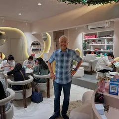 A happy client is our biggest reward. This gentleman is all smiles after his pampering session, standing in our bustling studio. We pride ourselves on creating a welcoming vibe for all.