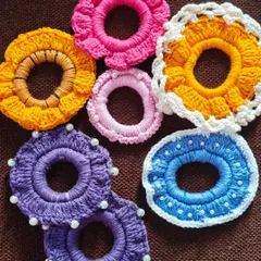 A colorful assortment of my floral and pearl-detailed crochet scrunchies. I make them in various designs, including sunflower patterns, simple ruffles, and ones dotted with tiny pearls for a touch of elegance.