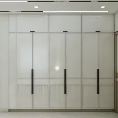 This minimalist wardrobe design features clean white panels with fluted details and long, elegant black handles. The integrated lighting at the top adds a soft glow, making the wardrobe a feature in itself.