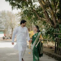 A candid shot of the couple walking together during their Haldi ceremony. The bride's green saree contrasts beautifully with the groom's white kurta, creating a classic Maharashtrian look.