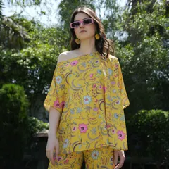 A bright yellow floral top and pants set, styled with modern pink sunglasses. The bold colors and sunny setting create a cheerful and eye-catching image for a summer campaign.