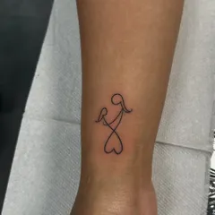 A beautiful single-line tattoo of a mother holding a child, forming a heart at the bottom. This minimalist design is a powerful symbol of a mother's endless love.