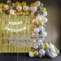A stylish and budget-friendly decoration in grey, white, and gold. The balloon garland paired with a gold shimmer curtain and a simple "Happy Birthday" banner is a great-looking, affordable option.