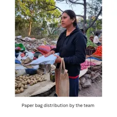 A volunteer hands out paper bags at a vegetable stall. These grassroots efforts are crucial for spreading awareness and making sustainable alternatives the norm in our community.