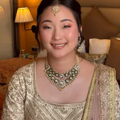 A beautiful smiling portrait. The soft pink eyeshadow and glowing cheeks give her a fresh, youthful, and celebratory look.