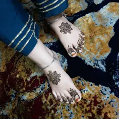 A top-down view of the mandala feet henna, looking elegant against the rich blue fabric.
