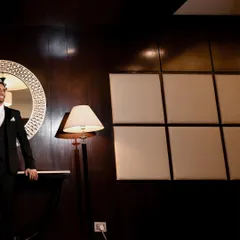A stylish groom portrait taken at a destination wedding. The dark, moody interior and the groom's confident pose make for a very modern and cool shot.