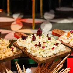 A close-up of our artisanal dips, including a creamy potato salad and hummus, served on wooden platters with breadsticks. Our buffets are designed to be both visually appealing and abundant.