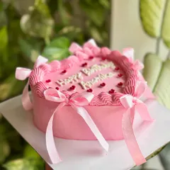 A side view of the pink birthday heart cake, showing how the ribbons cascade down the sides for a soft and celebratory balletcore look.