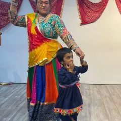 An instructor holds a young child's hand, guiding him through his first Garba steps during our Navratri celebration. These moments of shared cultural joy are what make our club a special place for families.