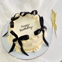 A vintage-style cake with a modern twist, featuring delicate piping and bold black ribbons. This design is a favorite for chic birthday celebrations.