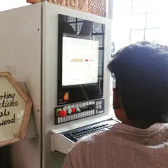 A student at the helm of a CNC machine, inputting commands and monitoring the progress of a digital fabrication project.