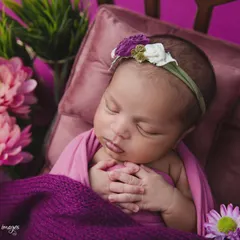 A closer look at the baby from the floral bed setup, focusing on her serene expression and the delicate headband. This highlights the intricate details of the theme.