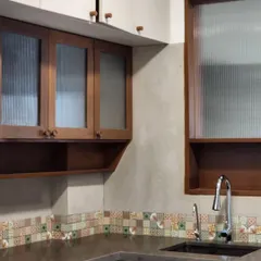 This kitchen corner features a mix of materials, including fluted glass, wood, and a colorful mosaic tile backsplash. The design balances functionality with a warm, handcrafted aesthetic.