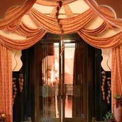 An entrance that makes a statement, with flowing drapes, hanging floral tassels, and vases of fruit and flowers creating a warm, inviting passage.
