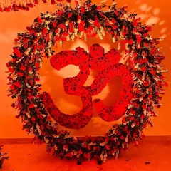 This floral 'Om' symbol, crafted from rich red roses and surrounded by a wreath of flowers, is a testament to my sacred floral art. It serves as a spiritual centerpiece, radiating devotion and energy throughout the Mata ki Chowki event space.