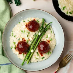 A creamy risotto with meatball "ornaments" and asparagus "trees". A playful and delicious take on a Christmas-themed dish.