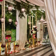 An elegant indoor-outdoor transition, with striped flooring, sheer white drapes, and hanging floral arrangements in a red and white palette.