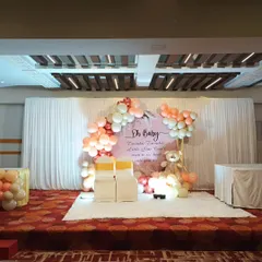A wide view of the baby shower stage in a banquet hall, featuring our elegant "Oh Baby" backdrop and seating for the parents-to-be.