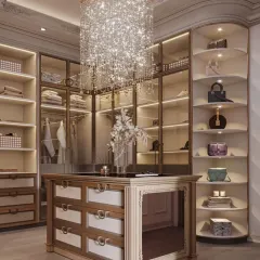 I design walk-in closets that are both a sanctuary and a statement. This space features a stunning crystal chandelier, custom glass-front cabinetry with internal lighting to display accessories, and a central island with organized drawer storage for a truly luxurious dressing experience.