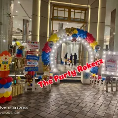 A grand entrance for a Carnival-themed party. I used a lighted arch, a welcome fence with signposts for games and photos, and clown-themed balloon pillars.