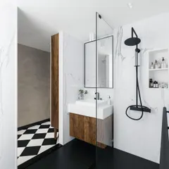 A view from the vanity area into the shower, showing the seamless glass partition and the consistent black-and-white theme.