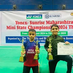 Two champions holding their trophies high. Adhiraj Shetty and his partner celebrate their Gold medal win in the Boys' Doubles U11 category at the Yonex Sunrise Maharashtra Mini State Championship.