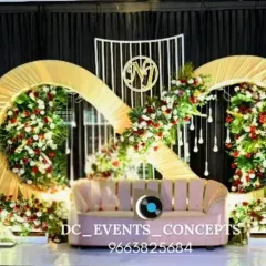 An infinity symbol-inspired backdrop for an engagement, decorated with red and white florals. This unique design includes hanging crystal elements and a custom monogram.