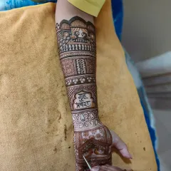 A work-in-progress shot. You can see the 'Griha Pravesh' text being added, a beautiful personal touch for the bride's new journey.