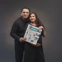 A creative pregnancy announcement. The couple holds a custom newspaper headline, "Blooming Beginning," sharing their joy in a unique and personal way. It's a fun prop that tells their story perfectly.