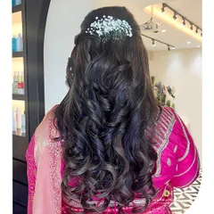 A beautiful half-up hairstyle with soft curls and fresh baby's breath, designed to perfectly complement a traditional saree for an elegant, feminine look.